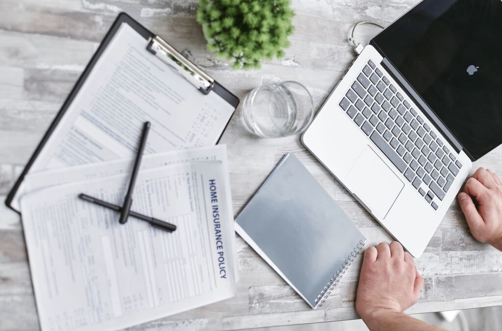 An insurance adjuster reviewing a claim file with documents and a computer — insurance adjuster injury claim